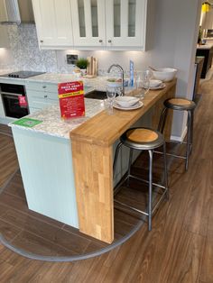 a kitchen with white cabinets and counter tops next to a wooden floor in front of an island