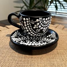 a cup and saucer sitting on top of a table next to a potted plant