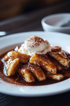 a white plate topped with bananas covered in chocolate sauce and ice cream on top of it