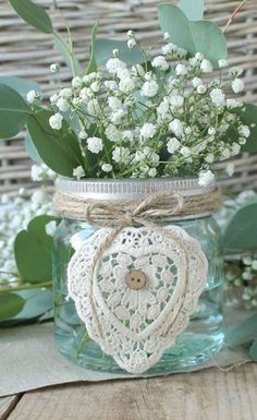 a mason jar filled with white flowers on top of a wooden table next to a wicker basket