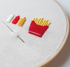 a close up of a embroidery on a hoop with french fries and ketchup