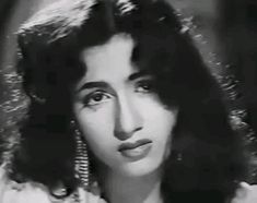 an old black and white photo of a woman with long dark hair wearing earrings on her head