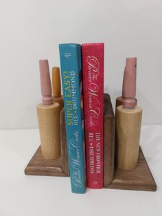 three books are sitting in front of each other on a wooden stand with pink and blue covers