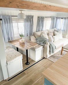 a living room filled with furniture and a wooden table in front of a window on top of a hard wood floor