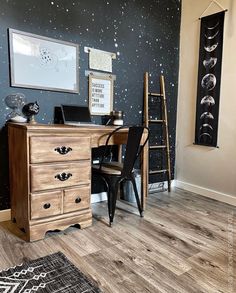 a space themed home office with black and white stars on the wall, wooden desk and chair