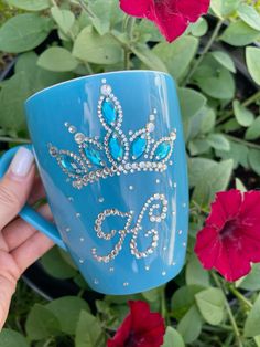 a hand holding a blue coffee mug in front of flowers