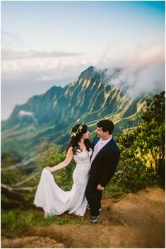 a bride and groom standing on top of a mountain