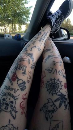 someone with tattoos on their legs sitting in a car