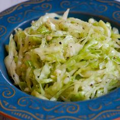 a blue bowl filled with coleslaw on top of a table