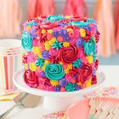 there is a colorful cake on the table with other plates and utensils around it