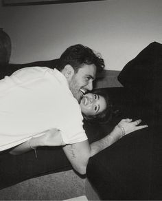 a man and woman laying on top of a couch smiling at each other's eyes