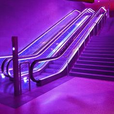 an escalator is lit up with purple lights