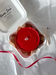 a red object in a white container with a red ribbon on the table next to it