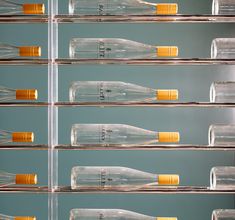 there are many empty glass bottles on the shelves in front of each other with yellow caps