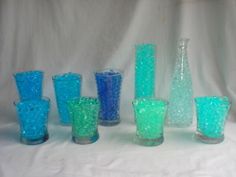 a group of blue and green glasses sitting on top of a white table next to each other