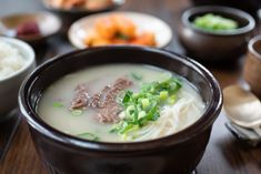 a table topped with bowls filled with soup and veggies