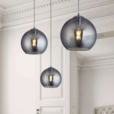 three light fixtures hanging from the ceiling in a room with white walls and flooring