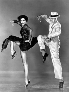 an old photo of two people dressed in costumes and hats, one is dancing with the other