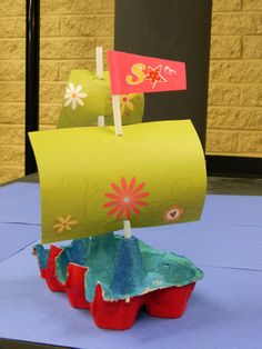 a paper boat is sitting on top of some red cups