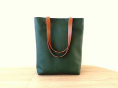 Large everyday casual vegan leather tote bag in forest green color with real leather handles. * Exterior: - High quality vegan/faux leather in beautiful intense dark green  color. * Interior: - Sandy beige ad white polka dot Italian natural cotton. * Two inside slip pockets for personal belongings like phone, keys, etc. * Real leather handles in dark chocolate brown/cognac brown/black attached with antique toned brass rivets * Closes with magnetic snap closure reinforced with natural leather * Additionally lined for better structure. Measurements: Height: 15 inches Width of the bag: 13 inches Width of the bottom: 3.5 inches Green Leather-lined Tote Shoulder Bag, Green Leather Shoulder Bag With Leather Handles, Everyday Green Leather Shoulder Bag, Dark Green Leather Bags For Daily Use, Green Bag With Rolled Handles For Daily Use, Green Satchel Bag With Rolled Handles, Green Tote Shoulder Bag For Everyday Use, Green Shoulder Bag With Rolled Handles For Travel, Green Tote Bag With Leather Handles