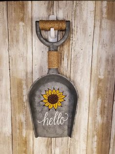 a metal bottle with a sunflower on it hanging from the side of a wooden wall