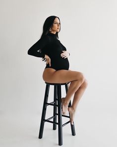 a woman sitting on a stool with her legs crossed and one leg bent over the bar stool