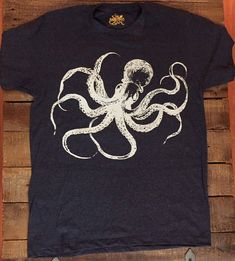 an octopus t - shirt with white ink on it sitting on top of a wooden table