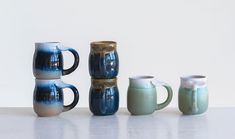 three mugs sitting next to each other on a white surface with no one around them