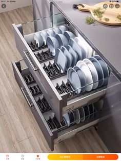 an open drawer filled with dishes on top of a wooden floor next to a counter