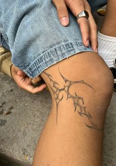 a person sitting on the ground with their legs crossed and tattoos drawn on her leg