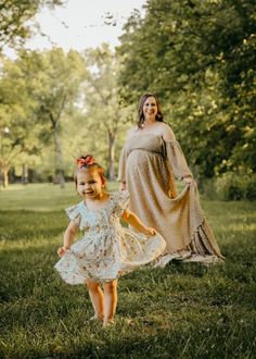 a pregnant woman and her daughter walking in the grass