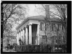 black and white photograph of an old house with columns on the front, surrounded by trees