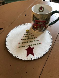 a coffee cup sitting on top of a table next to a christmas tree shaped coaster