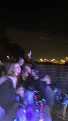 a group of people standing next to each other in front of a fence at night