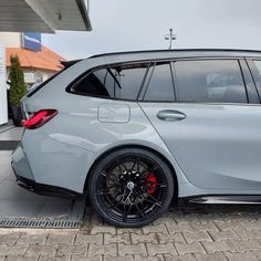 a grey car parked in front of a building with red rims on the tires