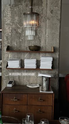 a table with glasses and plates on it in front of a wall mounted light fixture