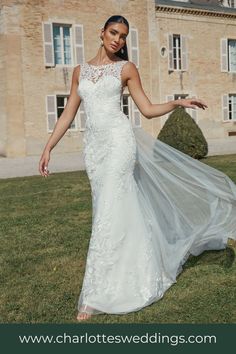 a woman in a wedding dress standing on the grass with her arms out and looking at the camera