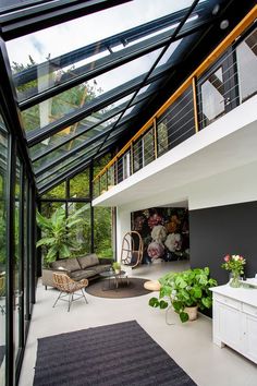 the inside of a house with glass walls and lots of plants on the ground floor