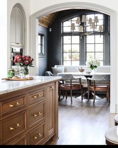 an open kitchen and dining room area with wooden cabinets, marble counter tops, and wood flooring