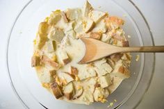 a wooden spoon in a glass bowl filled with batter and chopped up pieces of bread