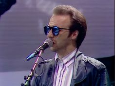 a man with sunglasses on singing into a microphone