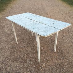 an old table sitting in the middle of a dirt field with no one around it