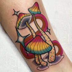 a colorful tattoo design on the leg of a woman's arm with an abstract mushroom