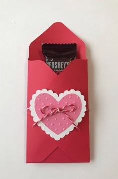 a red envelope with a pink heart and bow on the front that has hershey's chocolates in it