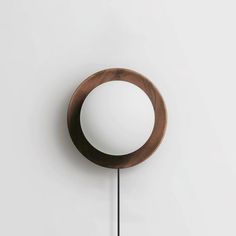 a round mirror mounted on the wall with a black metal pole in front of it