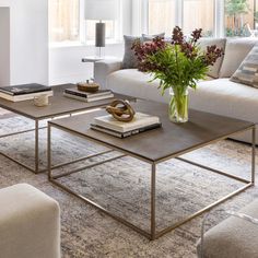 a living room filled with furniture and a vase full of flowers on top of a coffee table