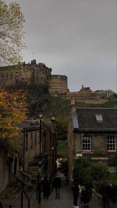 some people are walking down the street in front of an old castle