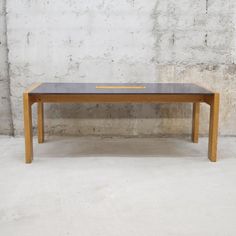 a wooden table sitting in front of a cement wall