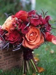 a bouquet of flowers sitting on top of a grass covered field next to an orange and red rose