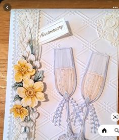 a card with two champagne glasses and flowers on the front, one is for anniversary